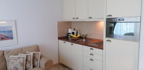una piccola cucina con armadi bianchi e lavandino di Sylter-Besserburg-App11 a Westerland