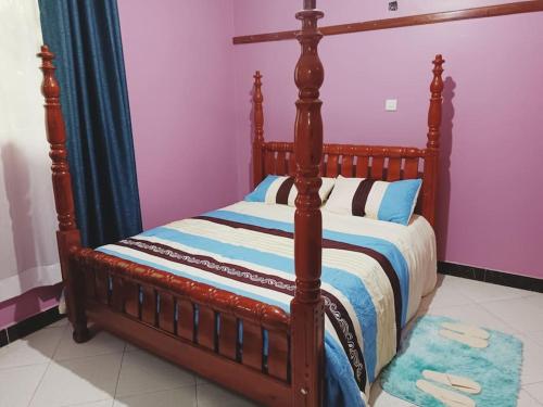a bed with a wooden frame in a room at the sanctuary apartment in Namulanda