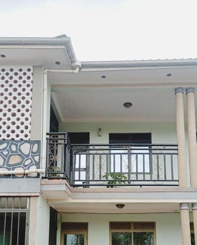 a white house with a balcony with a railing at the sanctuary apartment in Namulanda