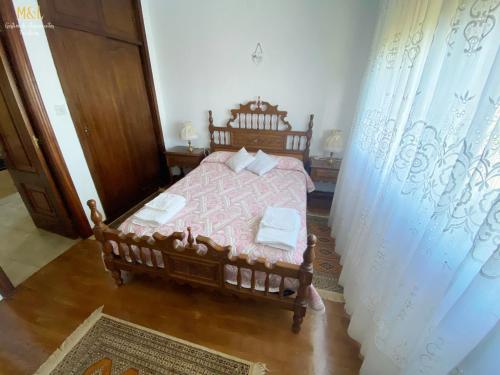 um quarto com uma cama de madeira com lençóis cor-de-rosa e almofadas brancas em La Casa de Lalo em Castrillón