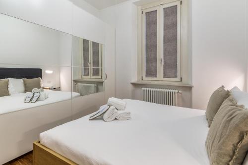 a white bedroom with two beds and a window at BePlace Apartments in Isola in Milan