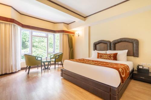 カリンポンにあるSummit Lillium Hotel & Spaのベッドとテーブルが備わるホテルルームです。