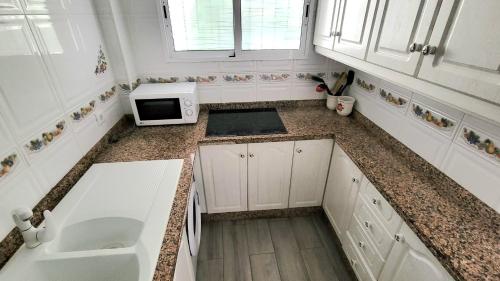 Una cocina con un fregadero y un microondas en una encimera. en Apartamento Sol de Carabeo, en Nerja