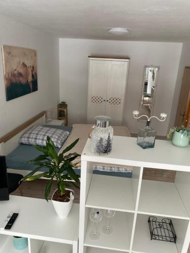 - une chambre avec un lit et un bureau blanc avec une plante dans l'établissement Ferienwohnung Shakira, à Penig