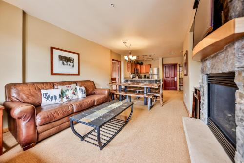 a living room with a leather couch and a fireplace at Zephyr Slopeside - 1504 condo in Winter Park