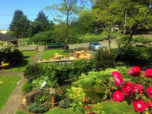 a garden with tables and chairs and red flowers at Ecola Creek Lodge in Cannon Beach