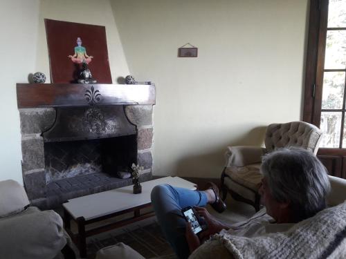 una mujer mayor sentada en una sala de estar con chimenea en Casa Echevarria en Los Cocos