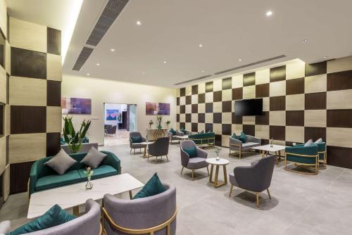 a waiting room with couches and chairs and a tv at Best Western Plus Al Qurayyat City Center in Al Qurayyat