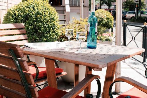 een houten tafel met twee wijnglazen en een fles bij Best Western Plus Hotel St. Raphael in Hamburg