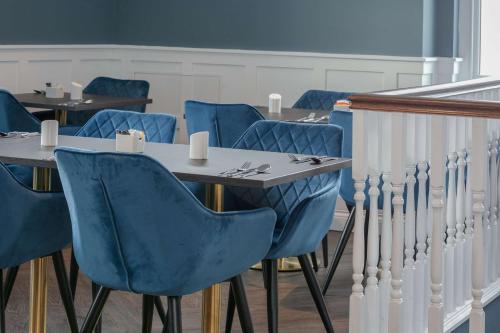 a dining room with blue chairs and a table at Best Western Hotel 99 in Blackburn