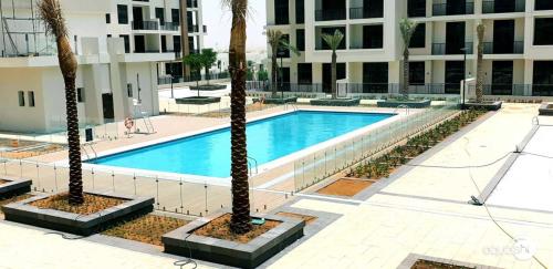 a swimming pool with two palm trees in front of a building at GuestReady - Flutes of Harmony in Town Square in Dubai