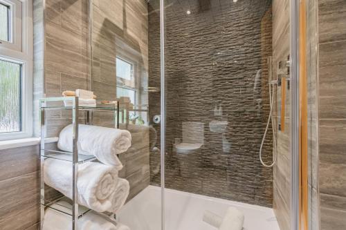 La salle de bains est pourvue d'une douche et de serviettes sur une étagère. dans l'établissement The Bank House- Luxury 3 bed cottage with hot tub!, à Silverdale
