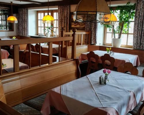 a dining room with two tables and chairs and windows at Gasthof Genosko in Spiegelau