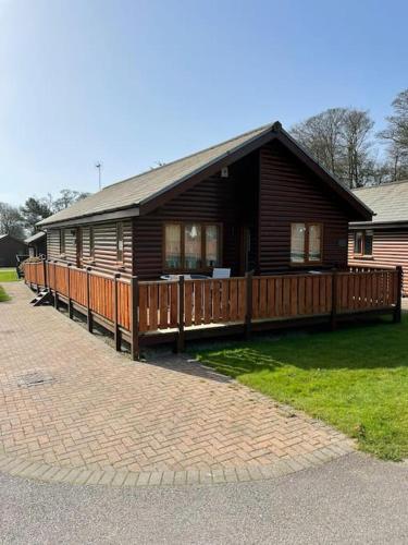 a large wooden house with a porch and a brick driveway at FourPar Lodge-Stunning lodge in a great location in Sewerby
