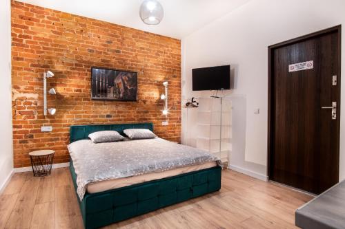 a bedroom with a bed and a brick wall at Dream Aparts - Studio przy Piotrkowskiej in Łódź