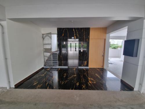 an empty room with a marble floor and a silver elevator at PPH Living KVR Residency in Tada