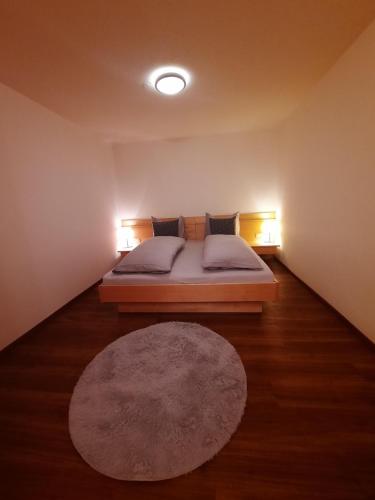 1 dormitorio con 1 cama con 2 lámparas y 1 alfombra en Schafferhäusl, Ferienwohnung, en Tux