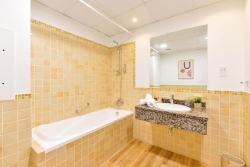 a bathroom with a tub and a sink and a mirror at Luxury JBR Shams · Full Sea View · Free 5* Beach Resorts Access! in Dubai