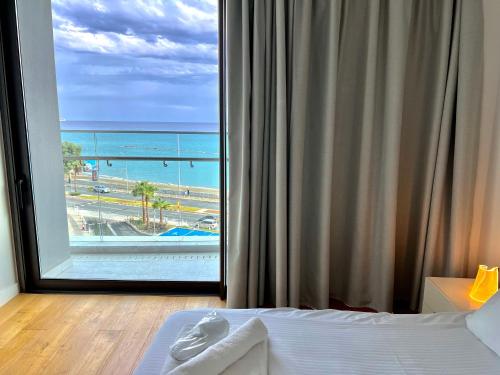 a bedroom with a large window with a view of the ocean at Del Mar Beachfront Boutique Residence in Limassol