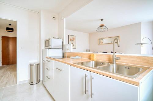 Logement Sarah في Courcouronnes: مطبخ أبيض مع حوض وثلاجة