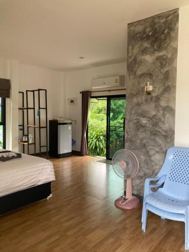 Oneandaman Resort في خاو لاك: غرفة نوم بسرير وكرسي ومروحة