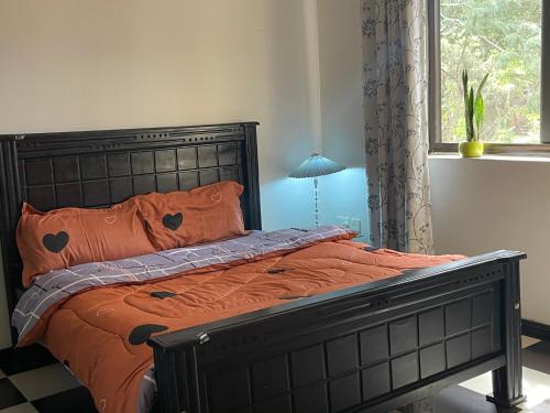 een bed met oranje lakens en oranje kussens in een slaapkamer bij Kim luxury apartment in Kampala