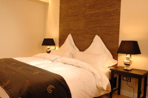 a bedroom with a bed with white pillows and two lamps at Hotel Zum Zeppelin Hamburg in Hamburg