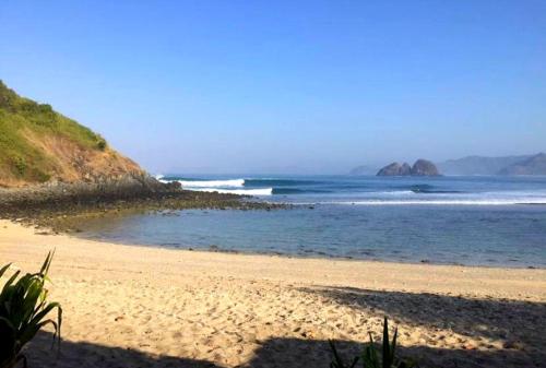 a beach with the ocean and mountains in the background at Drift Hideaway in Kuta Lombok