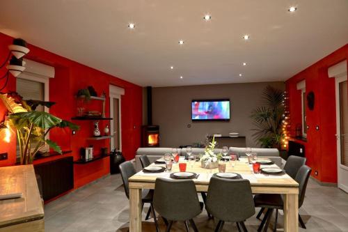 een eetkamer met een tafel en rode muren bij Gîte des Zèbres Aventuriers... in L'Etang-Bertrand