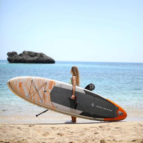 a woman is walking on the beach with a surfboard at Gîte des Zèbres Aventuriers... in L'Etang-Bertrand