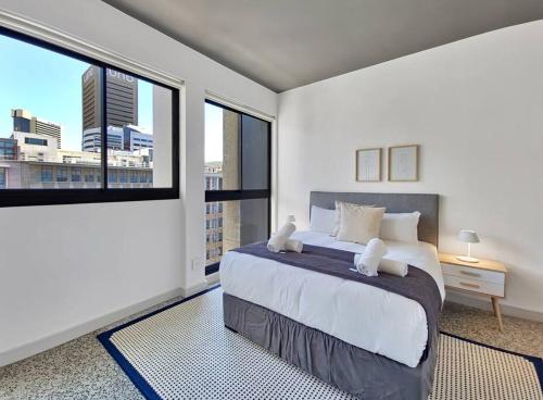 a bedroom with a large bed and large windows at 9th floor views, couples dream- wifi-pool in Cape Town