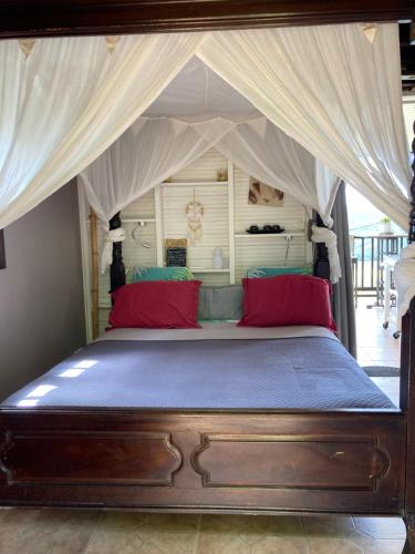 - une chambre avec un lit à baldaquin et des oreillers rouges dans l'établissement Muscade lodge, au Marin