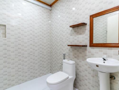 a bathroom with a toilet and a sink and a mirror at Maafolhey Han'dhaan - Ukulhas in Ukulhas