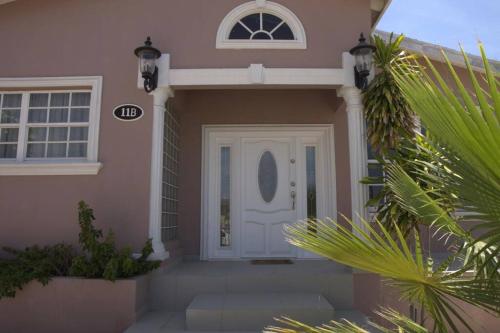 a pink house with a white door and a palm tree at Beautiful house in Sabana Basora Aruba! in Savaneta