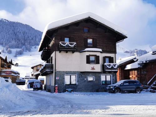 un bâtiment recouvert de neige avec une voiture garée devant dans l'établissement Livigno Elisir Petit, à Livigno