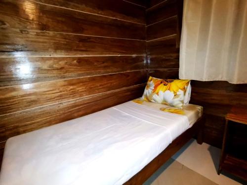 a small bed in a room with wooden walls at LADY GHAGHA ROOM RENTALs in San Vicente