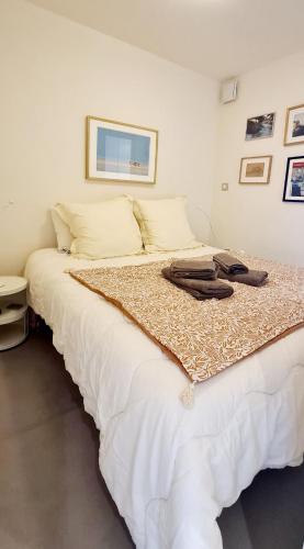 - une chambre dotée d'un grand lit blanc avec des vêtements dans l'établissement SUPERBE APPARTEMENT VUE MER - PLAGE, PISCINE et TENNIS PRIVE, à Bandol