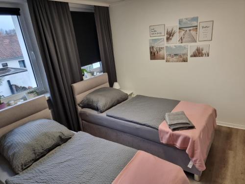 sypialnia z 2 łóżkami i oknem w obiekcie Gästehaus-Ferienwohnung-Appartement mit Terrasse - Nähe Kliniken/ Herzzentrum w mieście Bad Oeynhausen