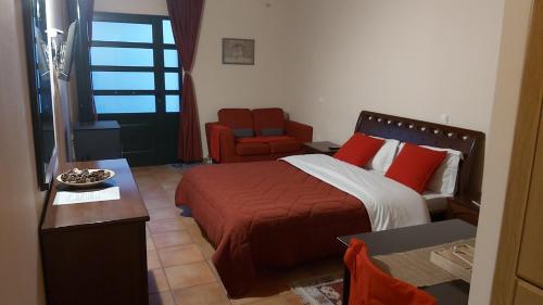 een slaapkamer met een bed met rode kussens en een stoel bij STYGA APARTMENTS in Kalavrita
