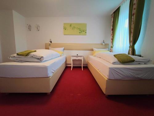 two beds in a room with a red carpet at Room in BB - Pension Forelle - double room in Forbach