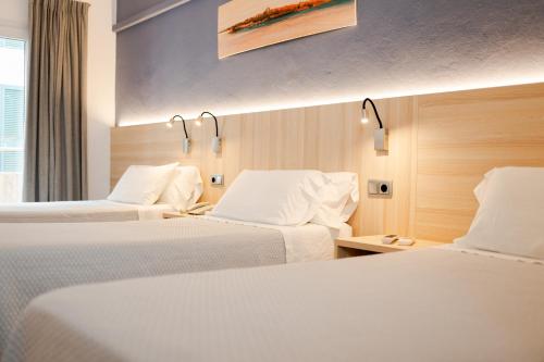a hotel room with two beds with white sheets at Eurohotel in Mahón
