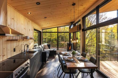 eine Küche und ein Wohnzimmer mit einem Tisch und Stühlen in der Unterkunft Le Zéphyr - Domaine Maelstrom in Lac-Beauport