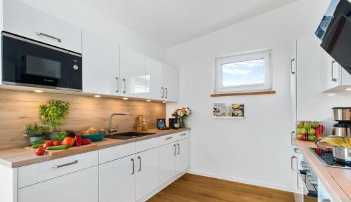 a kitchen with white cabinets and a sink and a window at Penthouse Hygge Meerblick am Strand in Olpenitz