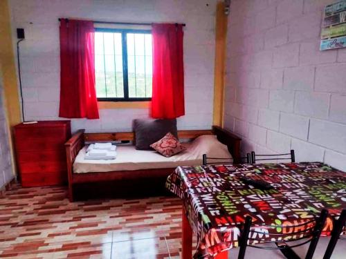 1 dormitorio con 1 cama y una ventana con cortinas rojas en Cabaña Buenos Recuerdos II en Villa Santa Cruz del Lago