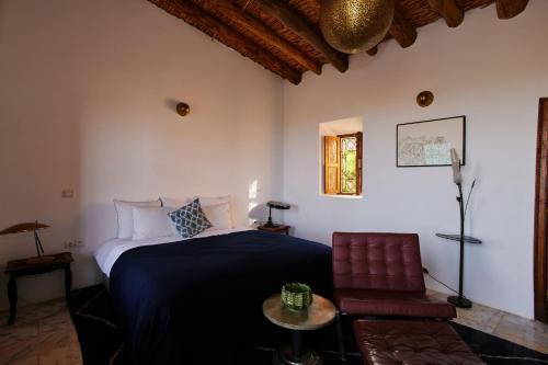 a bedroom with a bed and a chair and a table at Dar Imiri in Ourika