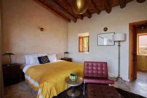 a bedroom with a large bed and a red chair at Dar Imiri in Ourika