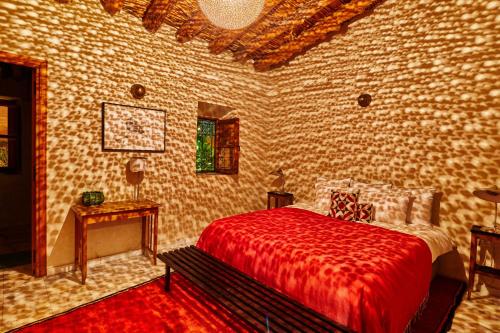 a bedroom with a bed with a red blanket and a table at Dar Imiri in Ourika