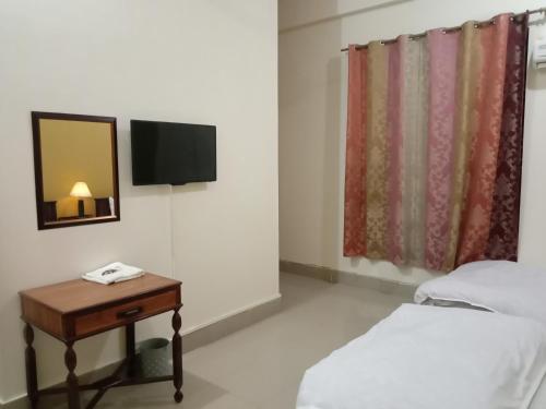 Victoria Guest House في بهاوالبور: غرفة بسرير وطاولة مع مرآة