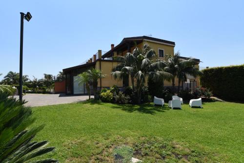 a house with palm trees and chairs in a yard at Feudogrande Bio Relais Hotel in Fiumefreddo di Sicilia