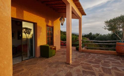 a porch of a house with a green chair and a glass door at Dar Imiri in Ourika